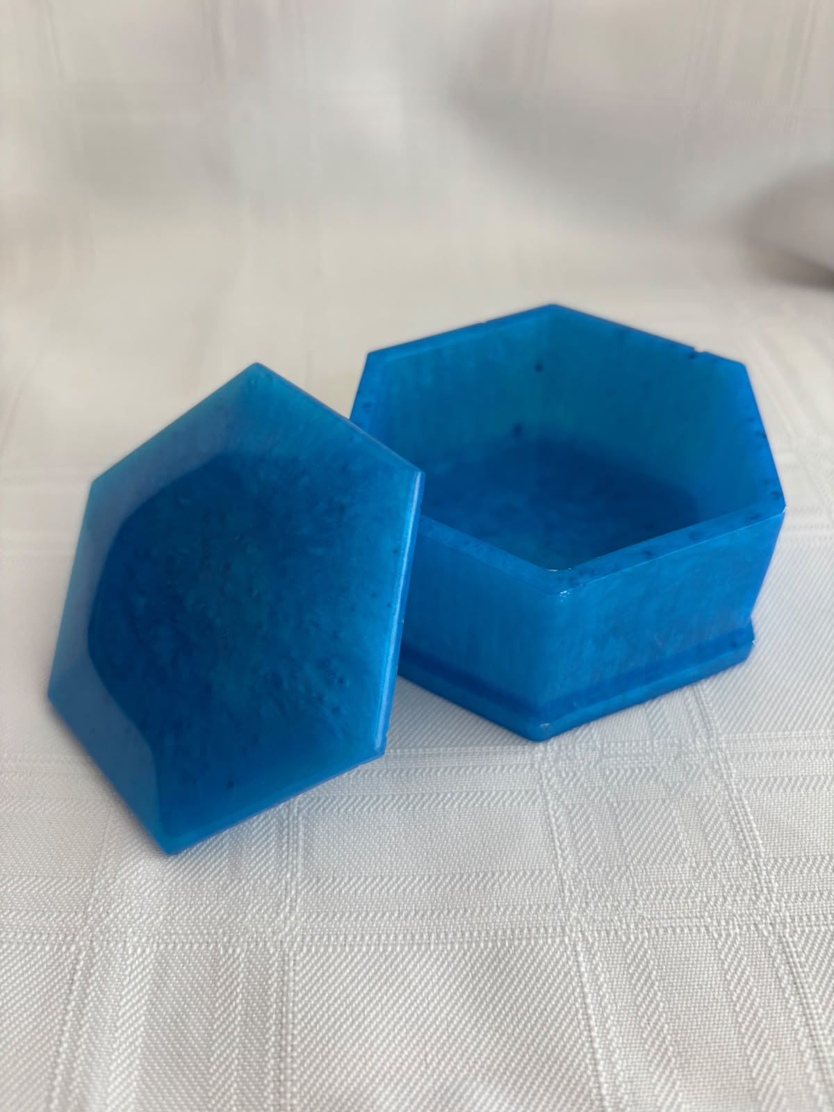 Hexagonal marbled blue resin box with its lid resting alongside