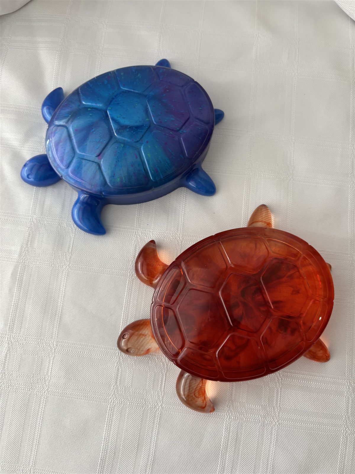 Two turtle-shaped resin trinket boxes, one blue and one amber, with lift-off shells