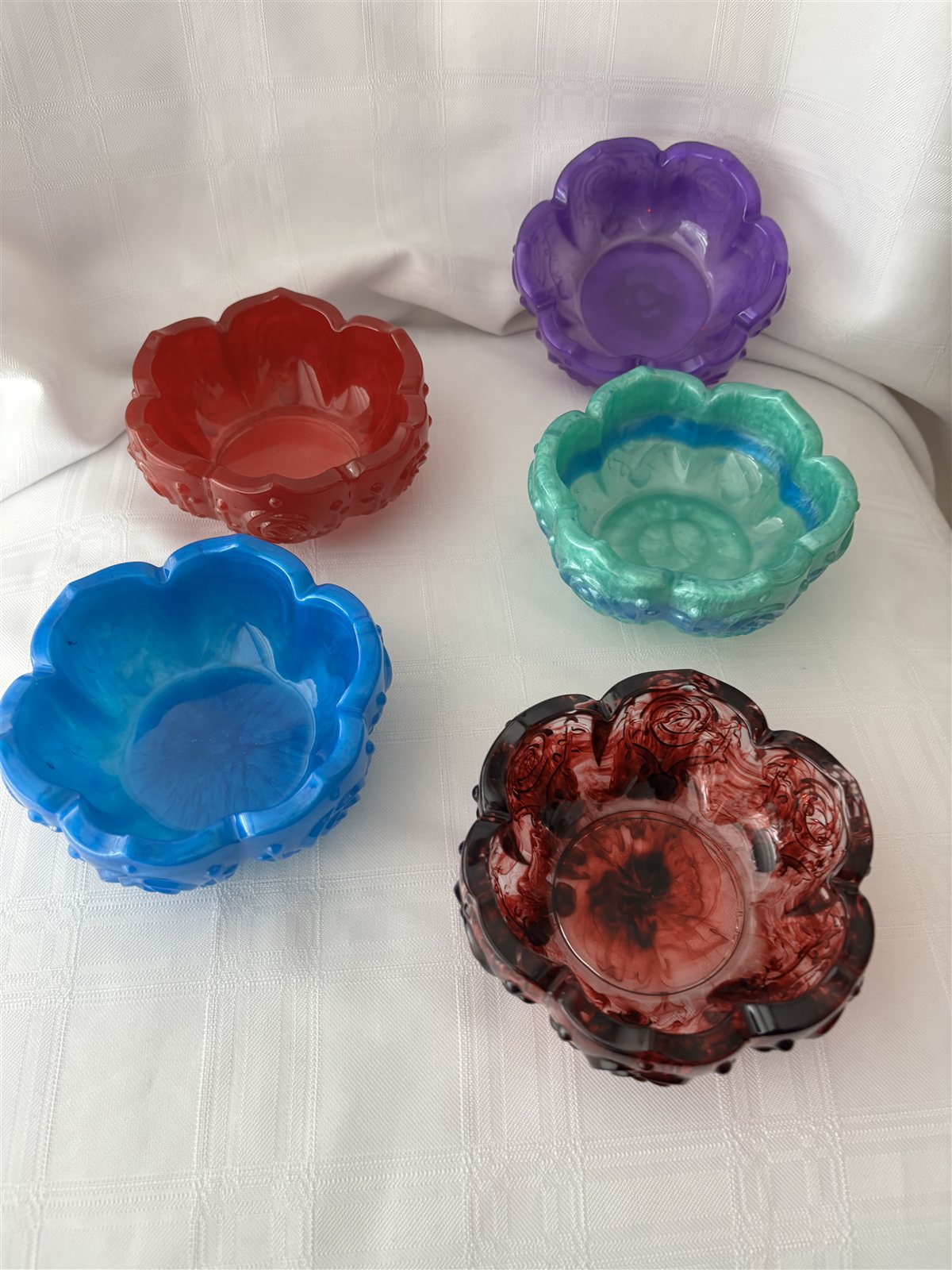 Five small flower-shaped resin dishes in purple, green, rose, red and blue