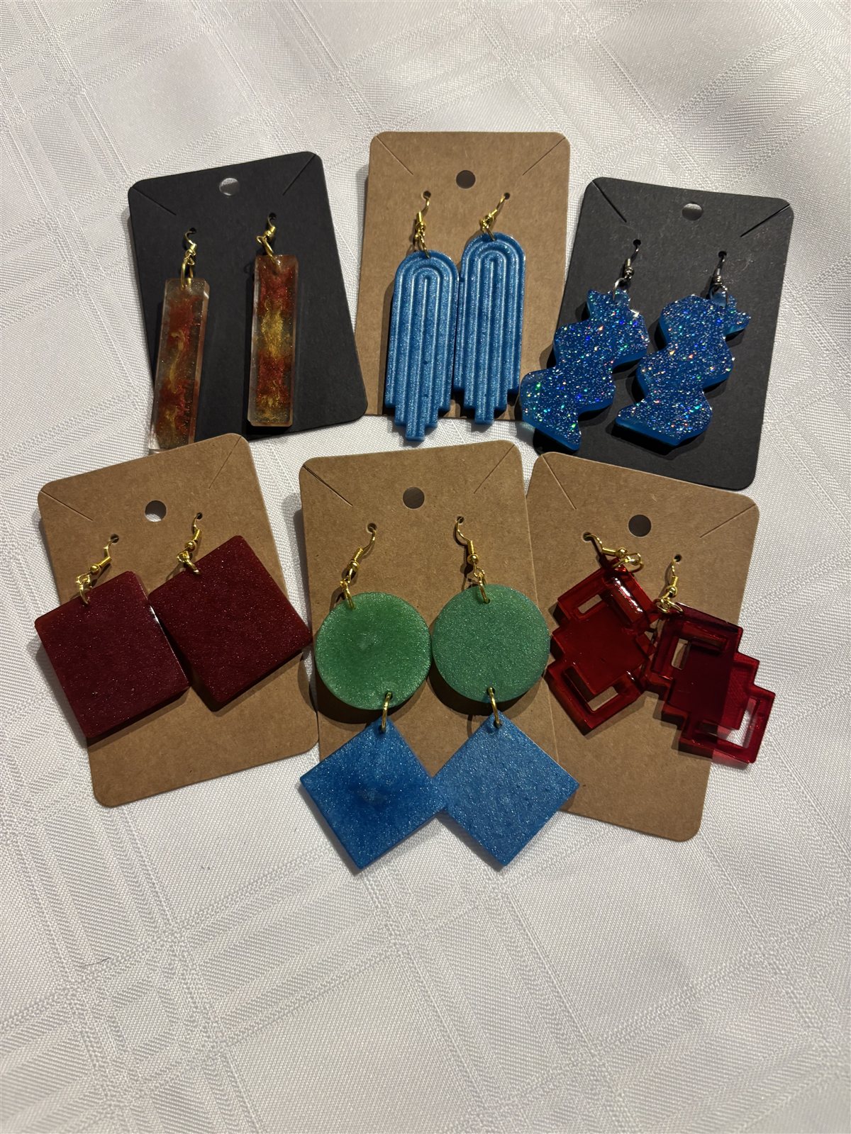 Seven pairs of resin drop earrings on cards, in rectangle, arch, glitter, square, circle and diamond shapes