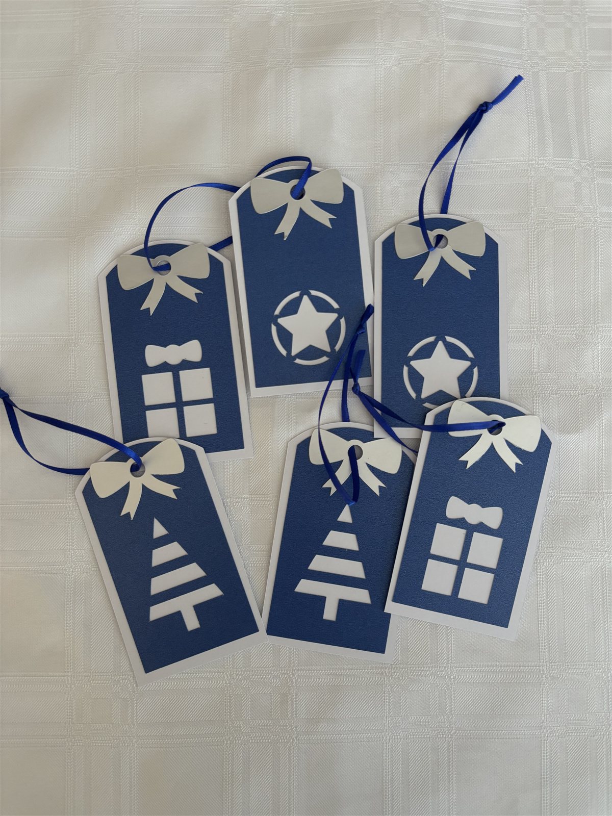 Six navy gift tags with white bows, cut with star, tree and gift-box designs