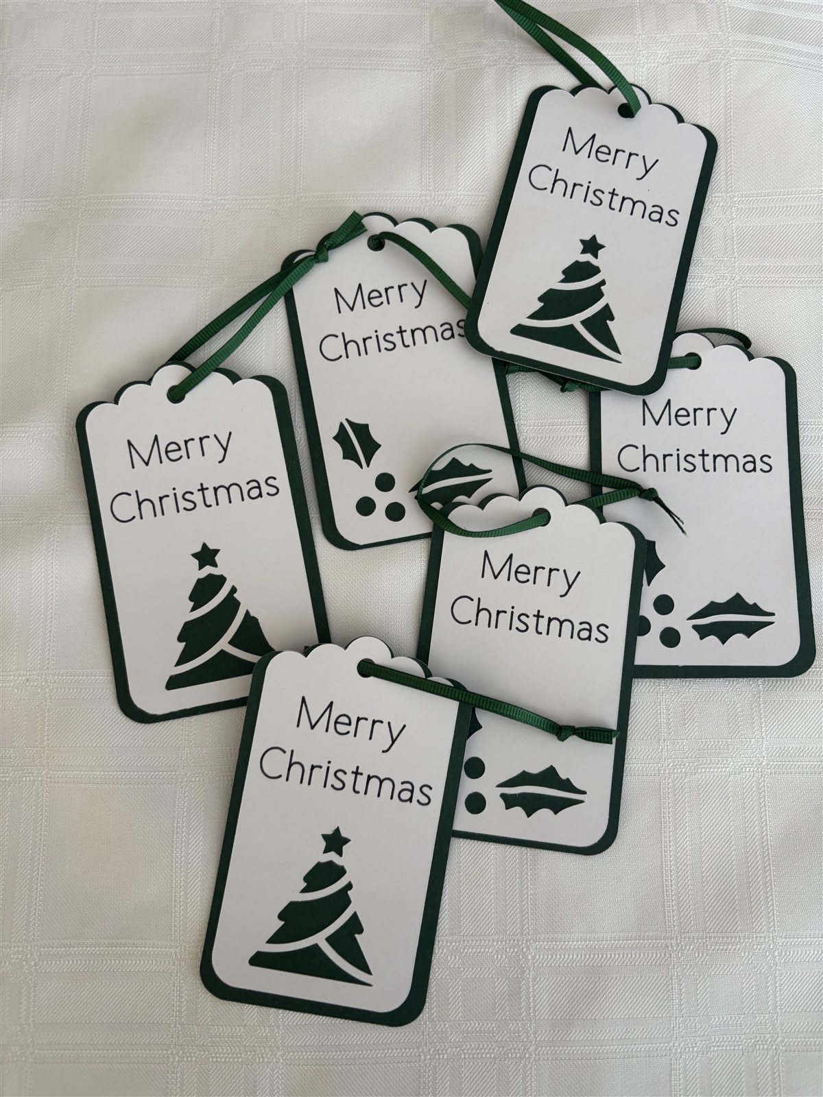 Six white scalloped-edge gift tags with a dark green border, reading Merry Christmas with a tree or holly design