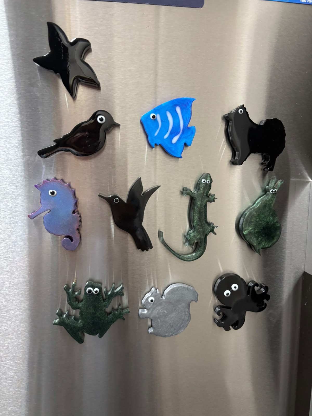 Eleven small resin animal magnets on a fridge door
