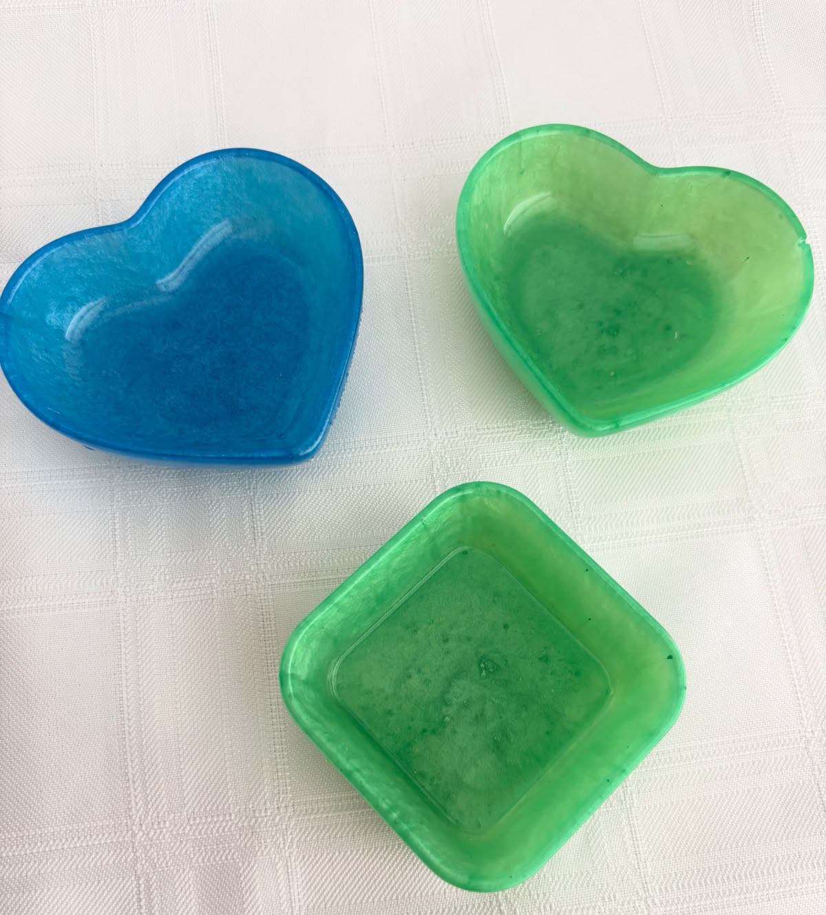 Three small resin trinket trays in blue and green, two hearts and a square